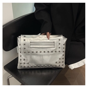 Dettaglio della pochette argento metallizzato con borchie quadrate e manico superiore