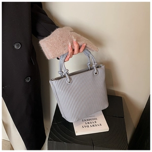 Detail of light blue pleated bucket bag with woven rope handles and round metal hardware