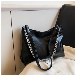 Detail view of black pleated leather tote bag with silver metal chain and shoulder strap