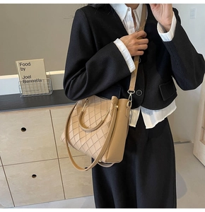 Detail of apricot bucket bag with diamond stitching paired with a black blazer