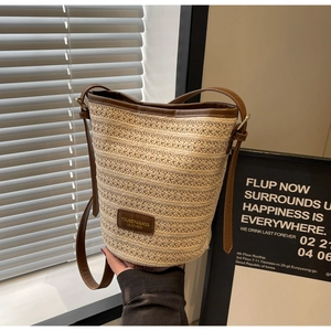 Detail showing the woven bucket bag texture with brown leather logo strap and trim