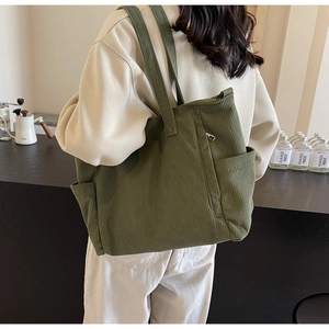 Detail of dark green corduroy tote bag showing side pocket and durable fabric texture