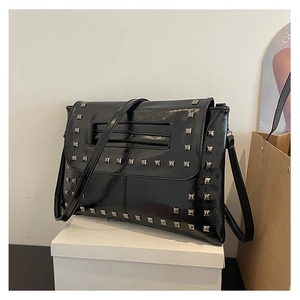 Dettaglio di borsa in pelle verniciata nera con borchie quadrate argentate e manico