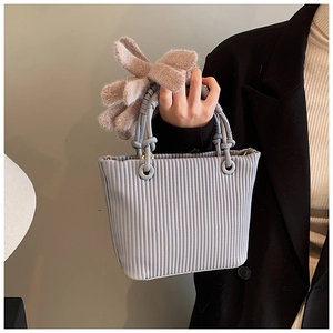 Detail view of a vertical pleated light blue bucket bag with a knotted handle design