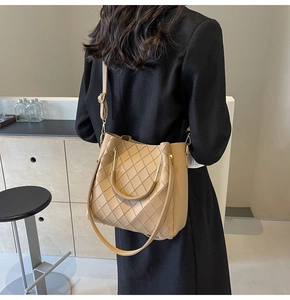 Detail of khaki bucket bag with diamond stitching and adjustable strap on a model