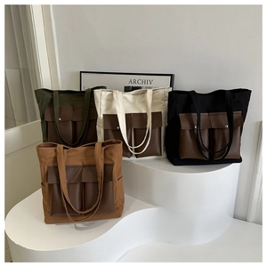 Detail of four multi-pocket canvas tote bags in green, beige, black, and tan on a display