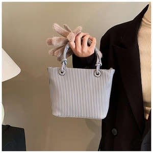 Detail of light grey pleated bucket bag showing vertical texture and silver metal eyelets