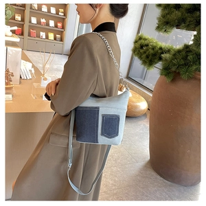 Detail of blue denim patchwork bucket bag with silver metal chain strap and pocket