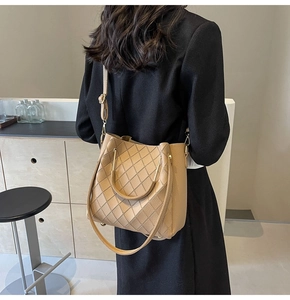 Detail of khaki quilted bucket bag with metal ring handles and lychee texture grain