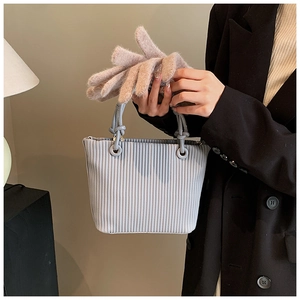 Detail view of vertical pleated bucket bag with metal ring handle and soft pink gloves