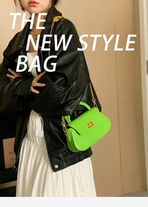 Detail of neon green crossbody bag with gold chain strap and metal turn-lock closure