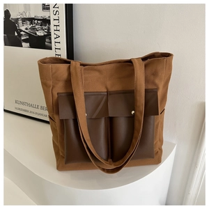 Close-up of canvas tote bag with brown leather pockets and durable metal buckles