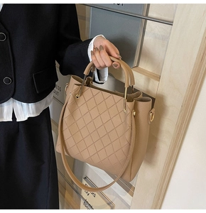 Detail of beige quilted bucket bag showing gold hardware and elegant pleat structure