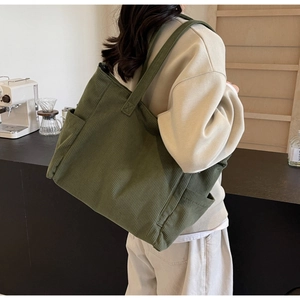 Detail of olive green corduroy tote bag showing side pocket and soft ribbed texture