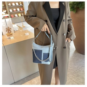 Detail view of retro denim bucket bag with blue patchwork and silver chain decoration