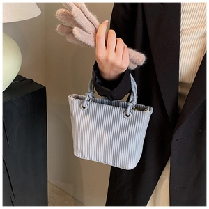 Detail of grey pleated tote bag with vertical textured fabric and knotted handles