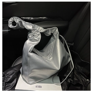 Detail of silver metallic cloud bag with pleated handles and shiny synthetic leather texture