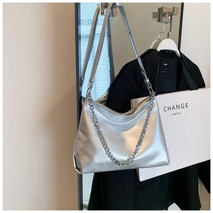 Detailed shot of silver metallic tote bag featuring dual leather strap and chunky metal chain