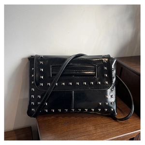 Dettaglio borsa a tracolla in pelle nera lucida con rivetti metallici quadrati argento