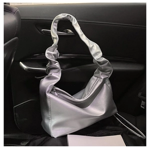 Detail of silver metallic pleated shoulder bag with scrunchie style strap in car interior