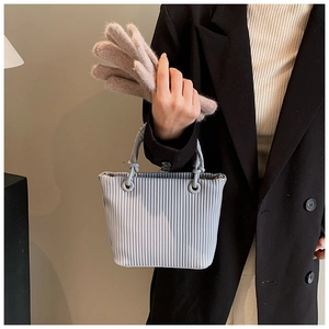 Detailed view of vertical pleated texture and braided handle on grey blue bucket bag
