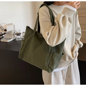Detail view of the deep green corduroy tote bag with side pocket and ribbed texture
