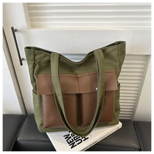 Detail of army green canvas tote bag with brown leather pockets and side pouches