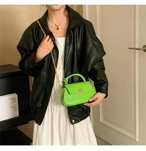 Detailed view of neon green crossbody bag with gold chain strap on a model outfit
