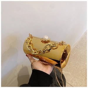 Detail of gold cylindrical evening bag featuring a pearl clasp and shiny mirror finish