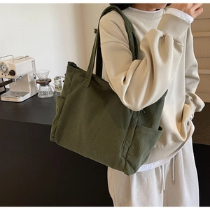 Deep green corduroy tote bag detail showing side pocket and large capacity on model