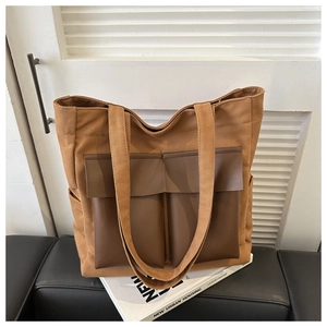 Detail of canvas tote bag featuring brown leather exterior pockets and durable top handles