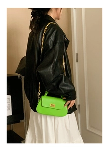Detailed view of neon green crossbody bag with gold chain strap on female model