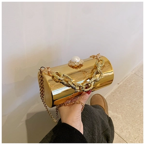 Detail of gold cylinder evening clutch with pearl handle, crystals, and dual chains