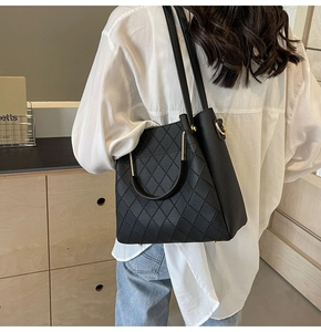 Close-up of a black leather bucket bag with diamond quilted texture and metal ring handle
