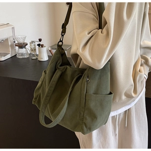 Detail view of olive green corduroy tote bag showing textured stripes and side pockets