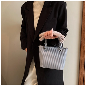Detail of light blue pleated bucket bag with vertical textured fabric and round rings