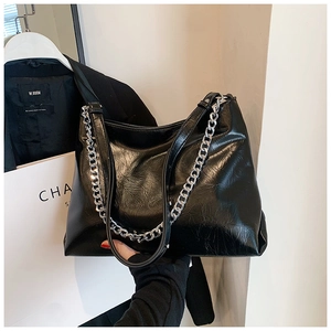 Detail of black pleated leather tote bag with silver chain strap for chic daily commute