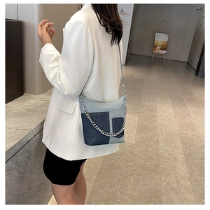 Detailed texture of blue denim patchwork bag with decorative silver metal chain strap