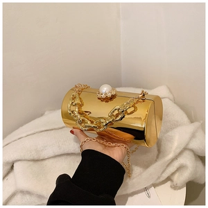 Detailed macro of golden mirror cylinder evening bag with pearl clasp and chain handle