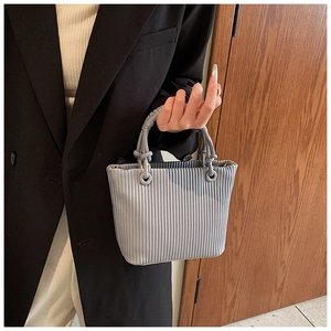 Chic light blue pleated bucket bag shown held by a model in elegant professional attire