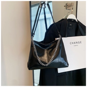 Detail of black pleated faux leather bag with silver chain and adjustable shoulder strap