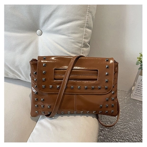 Dettaglio macro della borsa in pelle marrone con borchie argento e finitura lucida