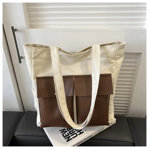 Detail view of large canvas tote bag with brown leather pockets and wide shoulder strap