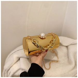 Macro detail of cylinder evening bag with gold mirror finish and pearl clasp accent