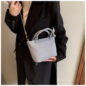 Vertical pleated texture detail on light blue crossbody bucket bag worn with a blazer
