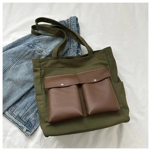 Close-up of military green canvas tote bag featuring dual front pockets with brown flaps