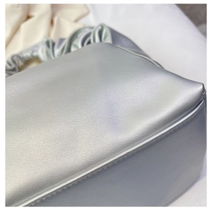Close-up of metallic silver baguette bag with pleated cloud handle and leather texture