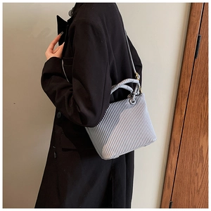 Detail shot of vertical pleated texture and round top handles on the light blue bucket bag
