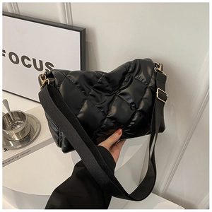 Dettaglio della borsa trapuntata nera con texture lucida e tracolla in nylon regolabile