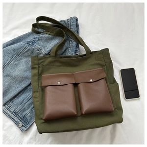 Detail view of olive green canvas tote bag featuring double brown leather front pockets